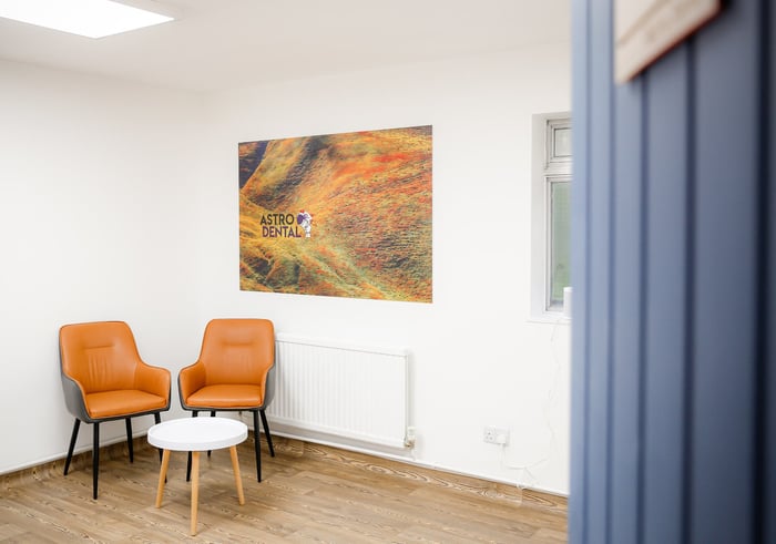 Seating corner at Astro Dental with tan chairs beneath a bright orange canvas